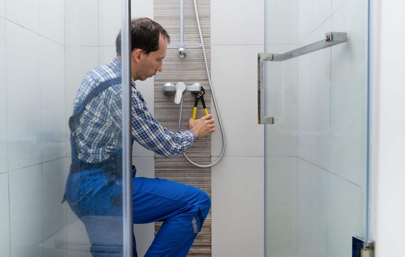 Plombier intervenant sur une installation de douche dans une salle de bain moderne