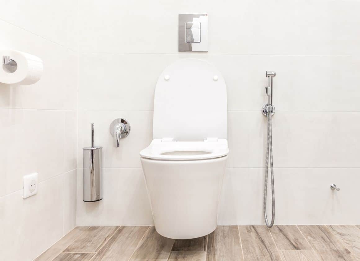 WC suspendu moderne installé dans une salle de bain avec douchette hygiénique et finitions soignées