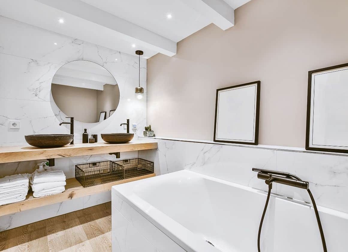 Salle de bain rénovée avec double vasque, baignoire moderne, miroir rond et finitions contemporaines